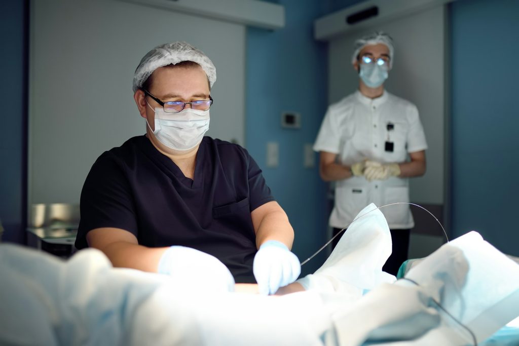 Professional vascular surgeon and assistant in the operating room of the clinic during vein surgery