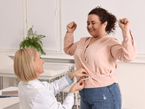 Happy Patient standing and measuring their waist in the doctor's office after semaglutide treatment