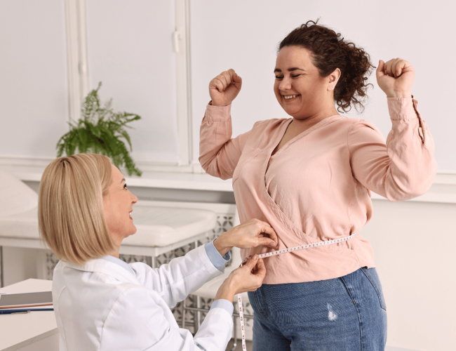 Happy Patient standing and measuring their waist in the doctor's office after semaglutide treatment